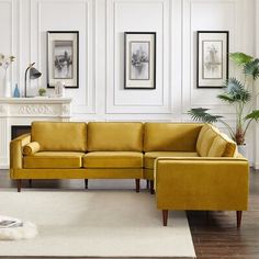 a living room with yellow couches and pictures hanging on the wall above it's fireplace