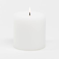 a white candle is lit on a white background