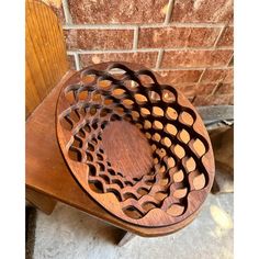 a wooden bowl sitting on top of a table next to a brick wall in a room