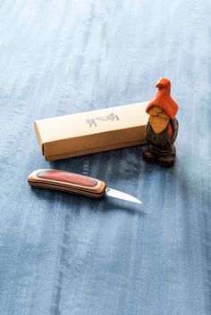 a small figurine sitting on top of a table next to a box and knife