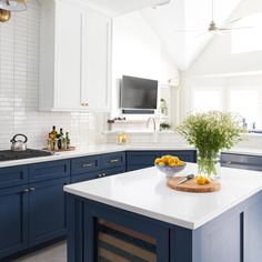 a kitchen with blue cabinets and an island in the middle is decorated with yellow flowers