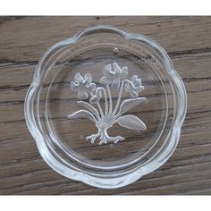 a clear glass bowl with flowers etched on the side and bottom, sitting on a wooden surface