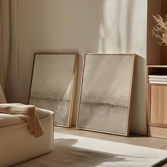 two framed pictures sitting on top of a floor next to a chair