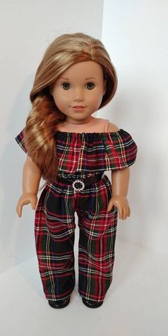 a doll with blonde hair is wearing plaid pants and a black top, she has her hand in her pocket