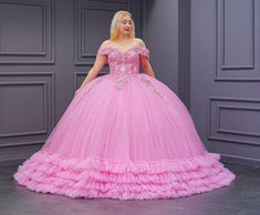 a woman in a pink ball gown is posing for the camera with her hands on her hips