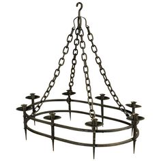 an iron chandelier with many candles hanging from it's center ring and chains on the bottom