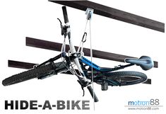 a bike hanging upside down from the ceiling in front of a sign that reads hide - a - bike