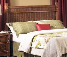 the bed is made with wicker headboard and red pillows on top of it