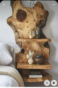 a wooden shelf sitting on top of a bed next to a vase and other items