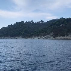 there is a boat that is in the water near some hills and trees on the shore