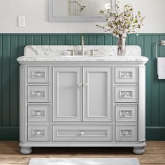 a white sink sitting under a mirror next to a wooden floor covered in rugs