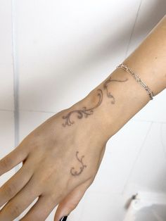 a woman's hand with a tattoo on it and a chain around the wrist