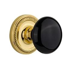 black and gold door knob with an ornate design on the front end, shown in polished brass