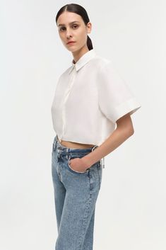 PRE-FALL 2024 WOMEN'S COLLECTION The Ryett Shirt in White. This short sleeve top offers a blend of classic tailoring and contemporary style. The neat collar and clean button-up front give a nod to traditional design, while the cropped cut and breezy short sleeves add a modern twist. The pure white fabric brings an air of freshness and versatility to any outfit, making it an ideal choice for a variety of occasions. Modern Fitted Tops With Button Closure, Fitted Modern Tops With Button Closure, Modern Fitted Blouse With Shirttail Hem, Modern Fitted Top With Button Closure, White Fitted Blouse With Shirttail Hem, Modern Tops With Shirttail Hem For Daywear, Fitted White Blouse With Shirttail Hem, Modern Formal Tops For Summer, Fitted Formal Tops With Shirttail Hem