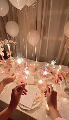 two people are sitting at a table with balloons and candles in front of the table