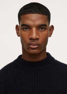 a man in a black sweater looks at the camera with an intense look on his face