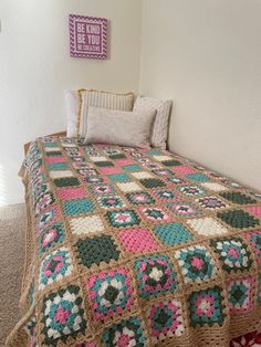 a crocheted blanket is on top of a bed in a room with white walls