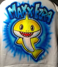 If you know a kid that loves the shark song and can't get enough of the little fella, let me airbrush a Baby Shark shirt for their birthday! Just type the name and age you want in the Personalization section. Or just type "no writing" and I'll leave the name and age off. I will paint the shark blue as in the pic. If you want a different color shark it's no problem. Just leave your directions to change it to the color you want in "Personalization".        Available white, grey, and even black tees. Please understand black costs $10 more than white or grey because of the extra time and paint involved. Looks just as bright on black as white or grey! I carry tee sizes from 6 Months to 5X.       Concerning adding writing to the other side for $8: If you don't want the back of the shirt to be bl Baby Shark Shirt, Airbrush Shirts, Baby Shark Birthday, Custom Airbrushing, Black Tees, Shark Shirt, Shark Birthday, Birthday Party Shirt, Love You Baby