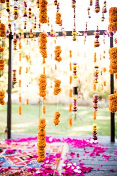 an outdoor area with flowers and decorations hanging from it's ceiling, along with pink petals on the ground