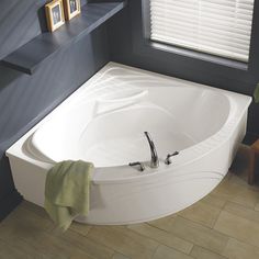 a bathroom with a large white bathtub next to a window