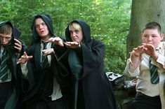 four young men dressed in harry potter costumes standing next to each other with their hands out