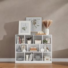 a white shelf filled with books and vases on top of a hard wood floor