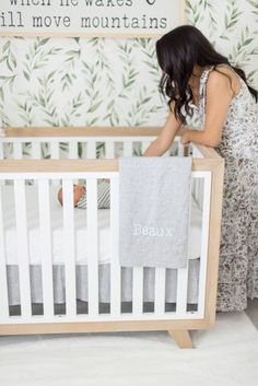 a woman standing next to a baby in a crib