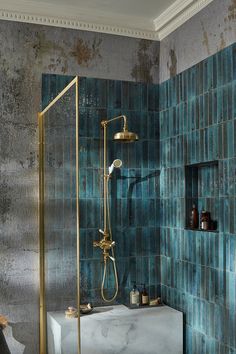 a blue tiled bathroom with gold fixtures and an antique tub, shower head, and hand held faucet