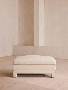 a white bench sitting on top of a hard wood floor next to a tall wall