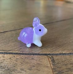 a purple and white toy elephant sitting on top of a wooden floor