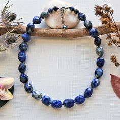 "Necklace length: 18\"L with 1.5\"L extender. Major beads: Lapis lazuli: faceted barrel shaped. Style: Beaded semi-precious stone necklace. Color: Blue color. Clasp: 13MM sterling silver rhodium plated clasp and closed jump ring. Finding: N/A. Workmanship: Hand beaded, and each bead is knotted in dark blue mixed cotton thread. Features: This classic style and timeless necklace feature large faceted lapis lazuli nuggets displaying natural flecks of pyrite that add a hint of shimmer. It is a great Lapis Lazuli Jewelry With Faceted Beads, Blue Faceted Oval Beads Jewelry, Healing Lapis Lazuli Jewelry With Faceted Beads, Handmade Sodalite Round Bead Necklaces, Handmade Sodalite Round Beads Necklace, Lapis Lazuli Beaded Necklace With Faceted Beads For Gift, Sodalite Gemstone Beads Necklaces, Spiritual Lapis Lazuli Necklace With Faceted Beads, Lapis Lazuli Faceted Bead Necklaces