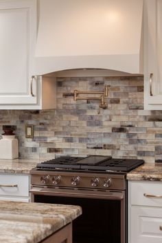 a stove top oven sitting inside of a kitchen next to white cabinets and counter tops