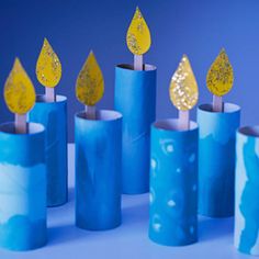 several blue candles with yellow leaves on them are lined up against a blue background,