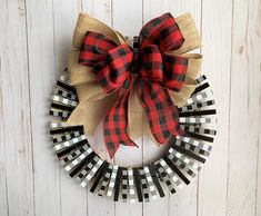 a red and black plaid wreath on a white wooden wall with a burluck bow