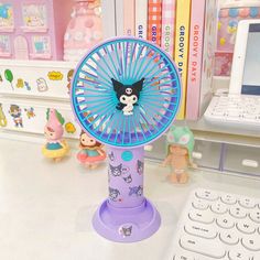 a toy fan sitting on top of a desk next to a keyboard