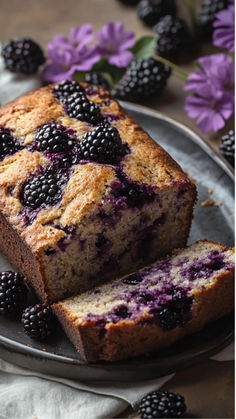 a loaf of blueberry bread on a plate with fresh blackberries