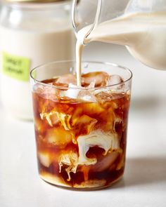 someone pouring milk into a glass filled with food