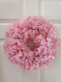 a pink wreath hanging on the front door with tulle ruffles around it