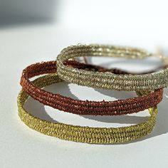 three different colored bracelets sitting on top of a white table next to each other