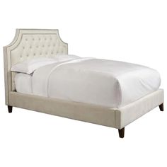 a bed with white linens and tufted headboard