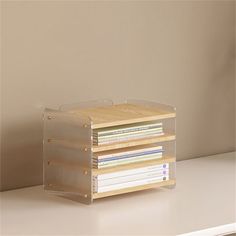 a stack of books sitting on top of a white table next to a wall with a lamp