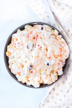 a bowl filled with fruit salad sitting on top of a white table next to a napkin