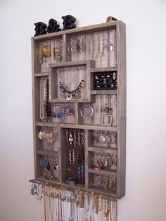 a wall mounted jewelry organizer with lots of necklaces