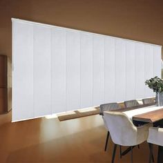 a dining room table with white chairs next to a large window covered in vertical blinds