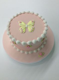 a pink cake with white frosting and a butterfly on top