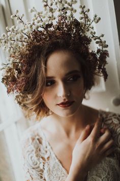 a woman with flowers in her hair wearing a white dress and posing for the camera