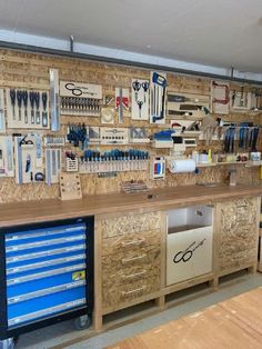 a workbench with lots of tools on the wall and drawers in front of it