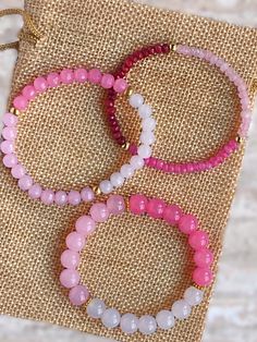 three bracelets with pink, white and grey beads on a burlock background