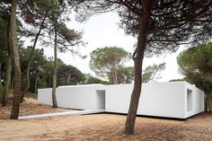 a white house surrounded by trees in the middle of a field with no grass on it