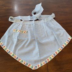 a blue and white striped dress with flowers on it sitting on top of a wooden floor